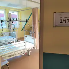 Szpitalna sala chorych z dwoma łóżkami i aparaturą medyczną.