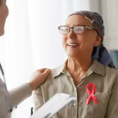 Lekarz wspiera pacjentkę z rakiem zrazikowym. Różowa wstążka symbolizuje nadzieję na skuteczne leczenie.