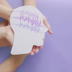 Dłonie trzymają profil głowy z falami EEG, symbolizującymi padaczkę nieświadomości u dorosłych.
