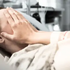 Osoba w szpitalu zakrywa twarz dłońmi. Zastanawia się, w jakim wieku zawał jest najgroźniejszy.
