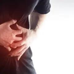 Dłońmi obejmuje brzuch, odczuwając ból. Może to być kolka jelitowa w ciąży, która jest częstym problemem.