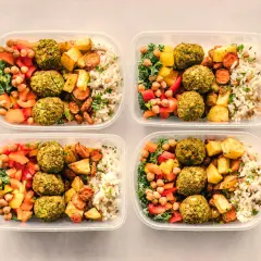 Cztery pojemniki z posiłkami: falafel, ryż, pieczone warzywa i sałatka. Idealny jadłospis na dietę dobrych produktów.