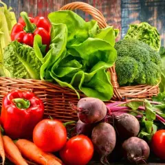 Koszyk pełen świeżych warzyw i owoców, idealnych na dietę owocowo warzywną: ananas, banany, marchew, papryka, pomidory, buraki, sałata, brokuły, kapusta, winogrona.