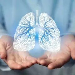 Dłonie trzymające świetlisty, schematyczny zarys płuc. Obraz sugeruje troskę o zdrowie i wyjaśnia, pneumonia co to jest.