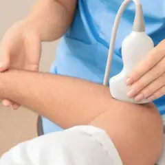 Badanie USG tkanek miękkich łokcia. Lekarz przykłada głowicę aparatu USG do przedramienia pacjenta, aby ocenić stan mięśni i ścięgien.