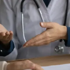 Lekarz omawia z pacjentem objawy, w tym uporczywy kaszel, który może być symptomem raka płuc.