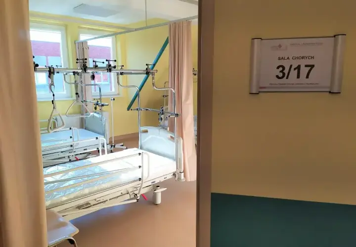 Szpitalna sala chorych z dwoma łóżkami i aparaturą medyczną.