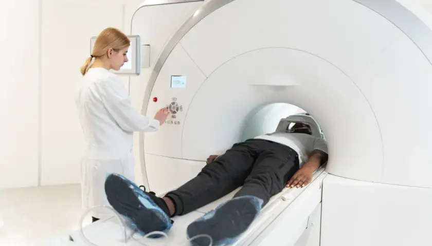 Pacjent leży w aparacie MRI, a technik kontroluje badanie. Choć rezonans magnetyczny jest bezpieczny, warto znać potencjalne skutki uboczne.