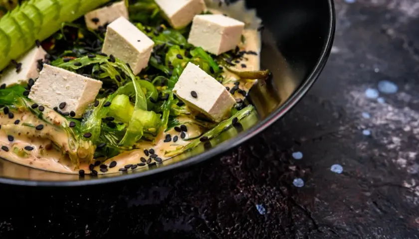 Sałatka z kostkami tofu, wodorostami i czarnym sezamem w kremowym sosie. Czy tofu jest lekkostrawne? Tak, to świetny wybór!