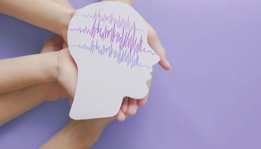 Dłonie trzymają profil głowy z falami EEG, symbolizującymi padaczkę nieświadomości u dorosłych.
