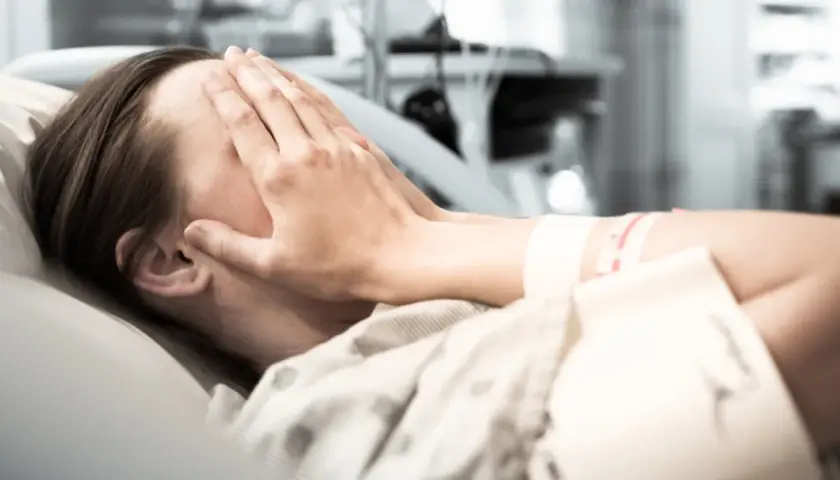 Osoba w szpitalu zakrywa twarz dłońmi. Zastanawia się, w jakim wieku zawał jest najgroźniejszy.