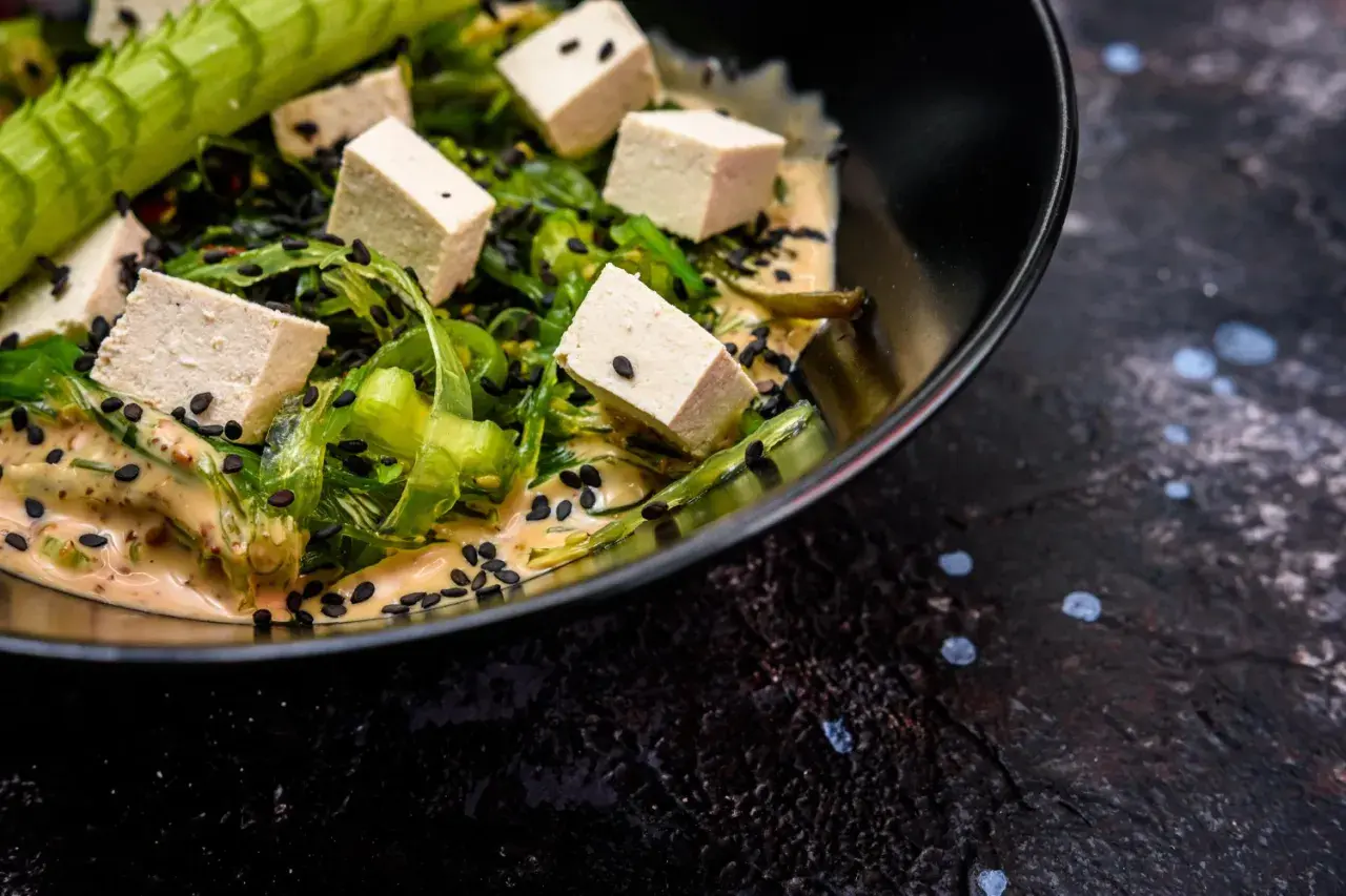 Sałatka z kostkami tofu, wodorostami i czarnym sezamem w kremowym sosie. Czy tofu jest lekkostrawne? Tak, to świetny wybór!