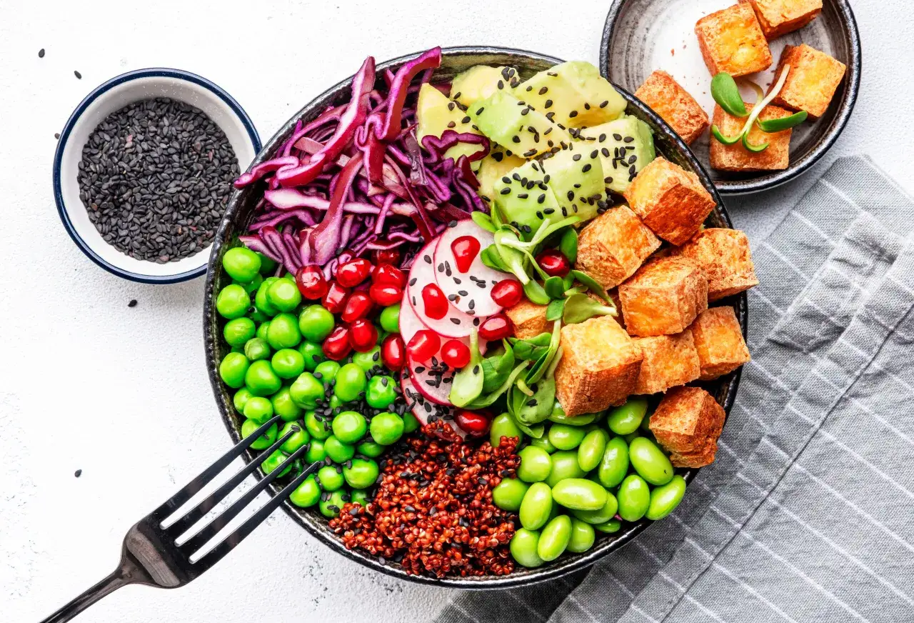 Kolorowa miska pełna zdrowych składników: pieczone tofu, edamame, groszek, czerwona kapusta, awokado, komosa ryżowa i nasiona. Tak właśnie co jedzą wegetarianie!