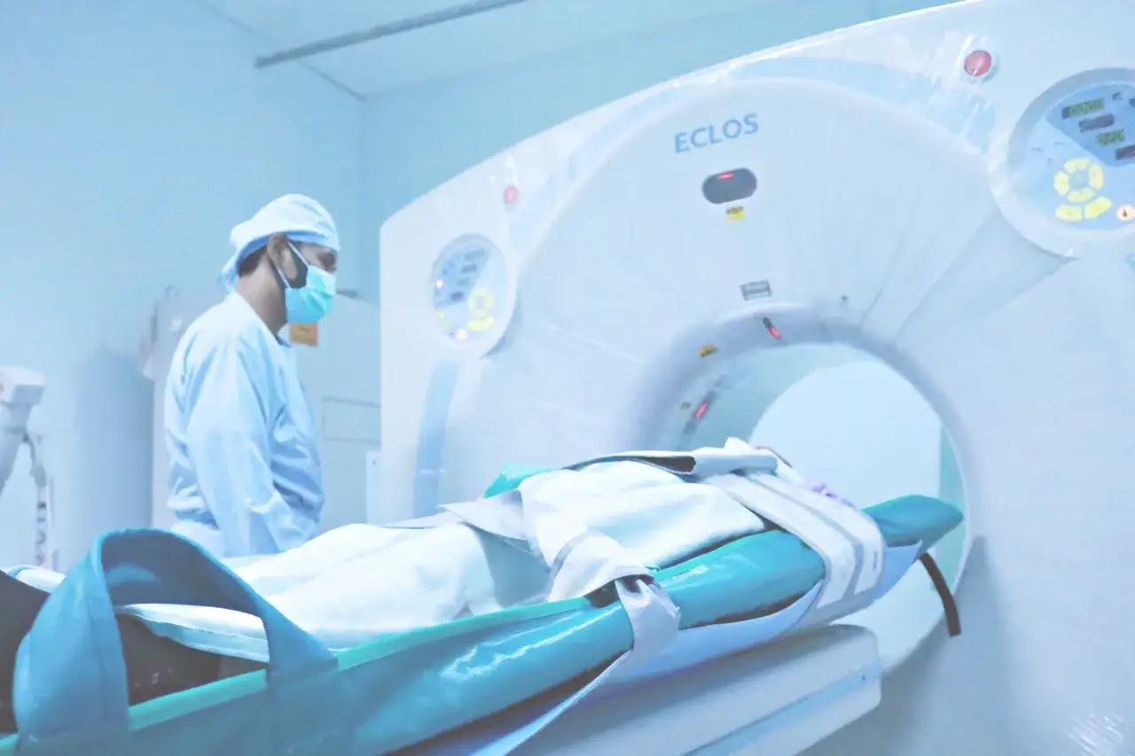 Pacjent na stole wjeżdża do aparatu tomografii komputerowej. Technik medyczny obserwuje proces, demonstrując, jak działa tomografia komputerowa.