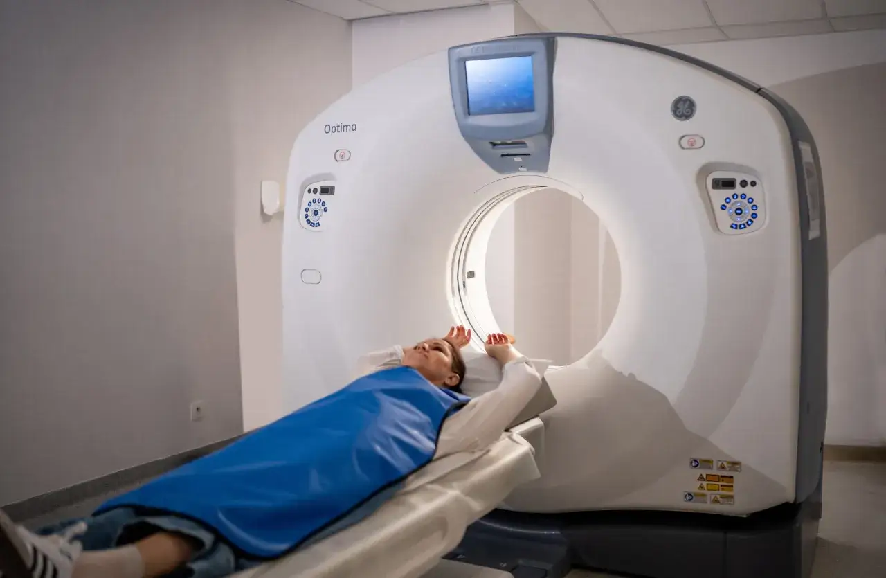 Pacjentka leży na stole tomografu komputerowego. Urządzenie Optima GE Healthcare pokazuje, jak działa tomografia komputerowa, tworząc szczegółowe obrazy wnętrza ciała.