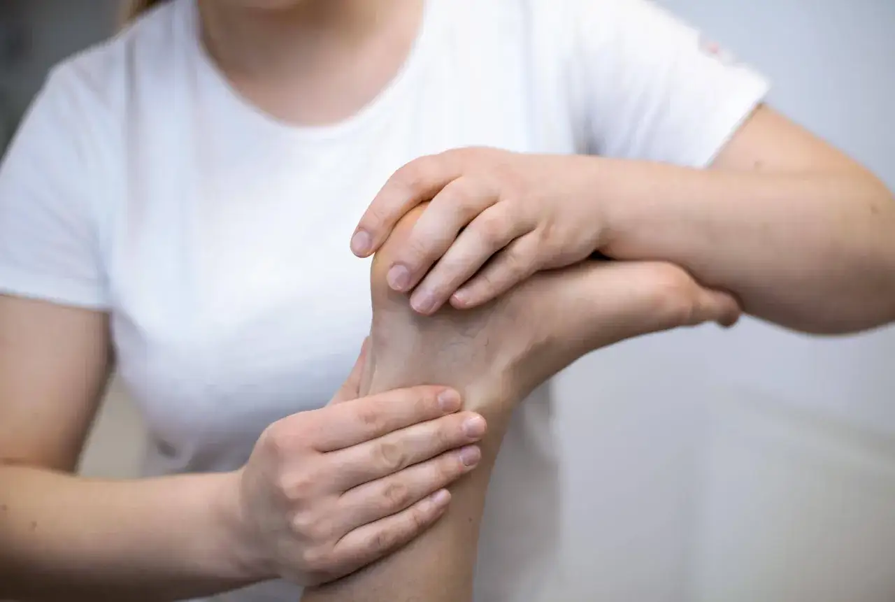Fizjoterapeuta bada stopę, szukając przyczyny bólu. Może to być pomocne w leczeniu co na naderwany mięsień.