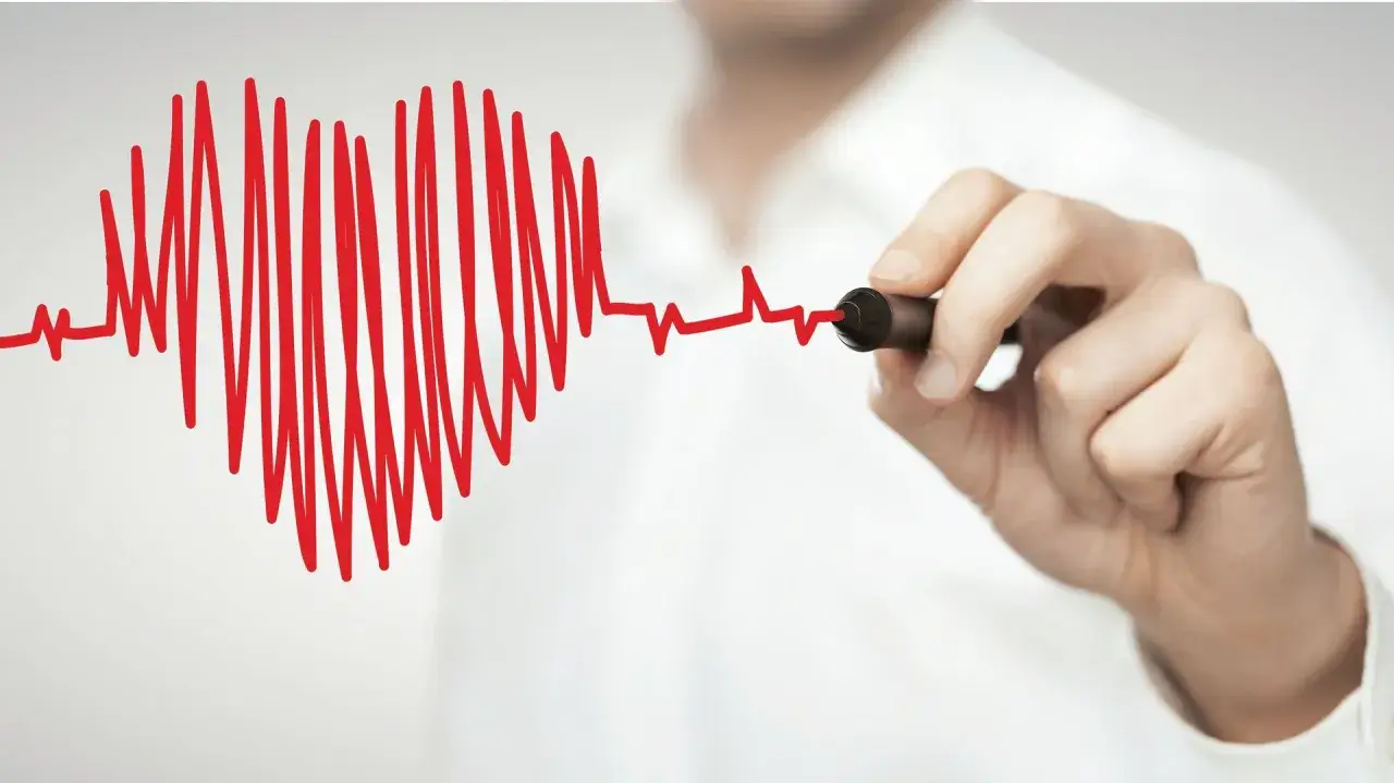 Dłoń rysuje czerwone EKG, które tworzy serce. Czy tachykardia jest groźna?