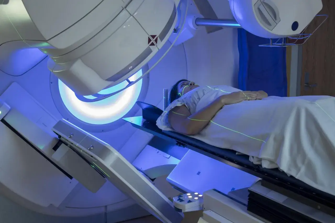 Pacjentka leży pod aparatem do radioterapii, który precyzyjnie naświetla zmienione chorobowo tkanki. Tak wygląda nowoczesna radioterapia.