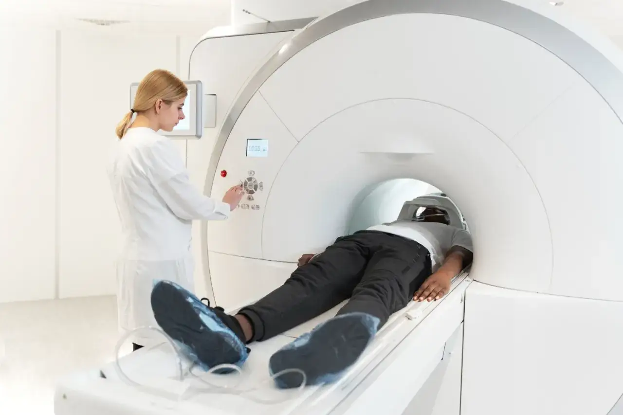 Pacjent leży w aparacie MRI. Lekarka obsługuje konsolę, monitorując badanie. Choć rezonans magnetyczny jest bezpieczny, warto znać potencjalne skutki uboczne.